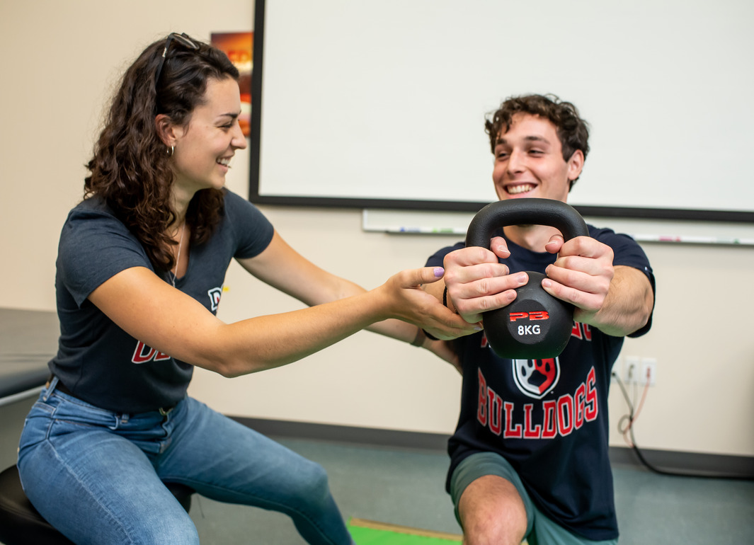 girl helping a patient lift a weight