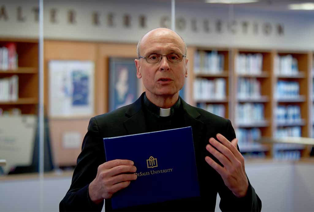 Father Jim holding a diploma