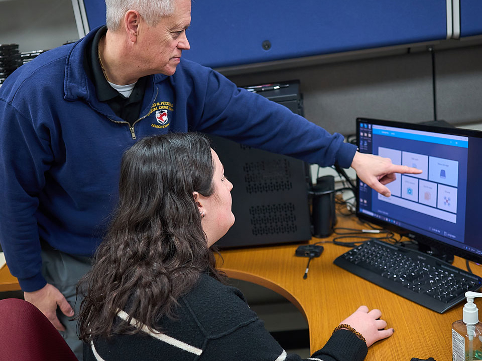 student and professor looking at a computer