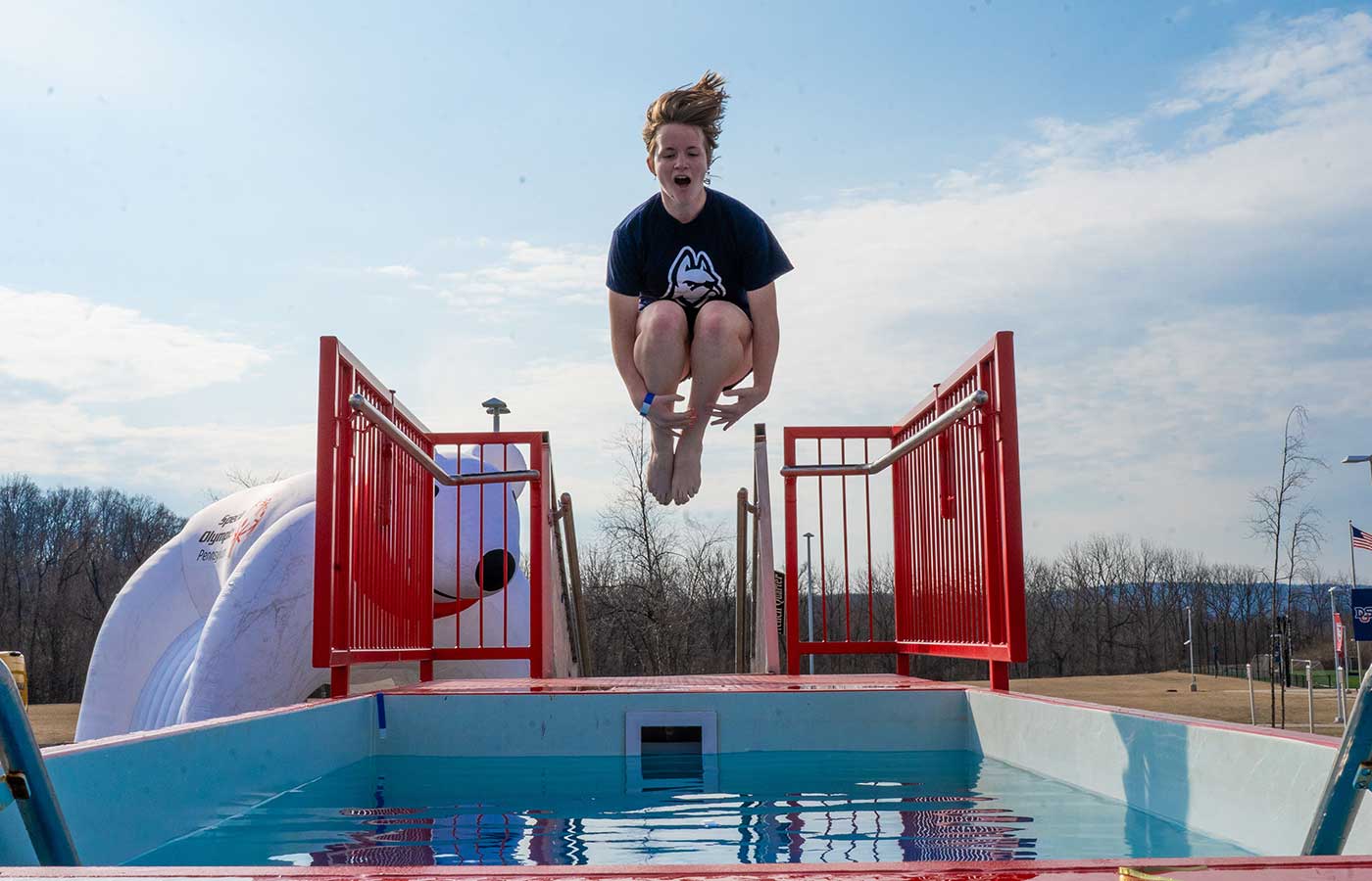 student jumping into pool