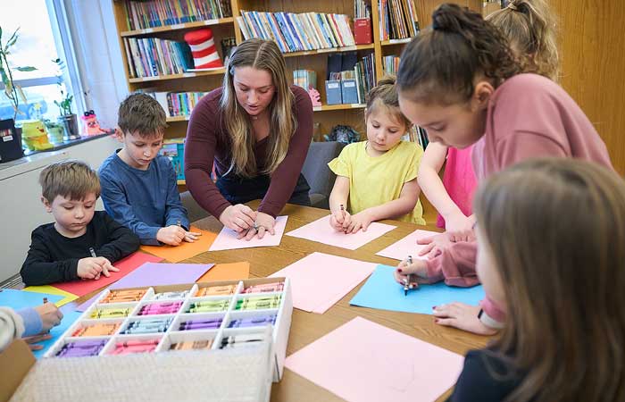 elementary school children drawing hands with teacher