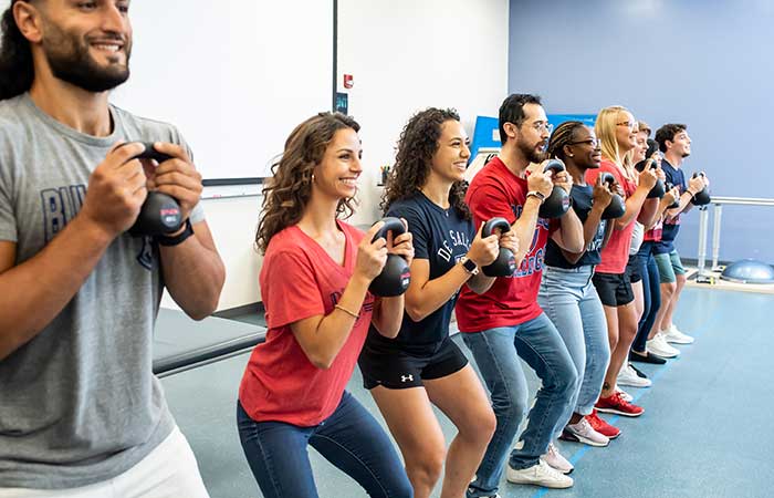 students lifting weights for a sport an exercise science class