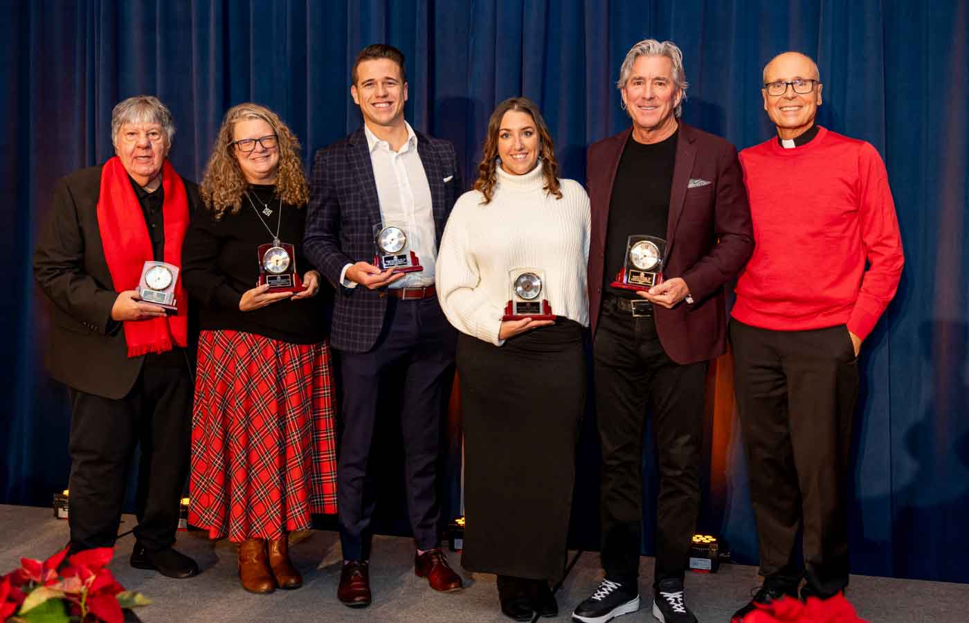 DeSales University Alumni Award honorees pose together on stage holding their awards.