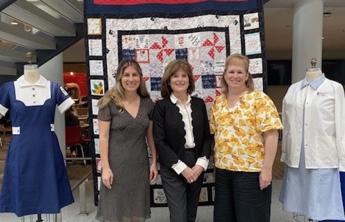 3 ladies standing in front of a quilt