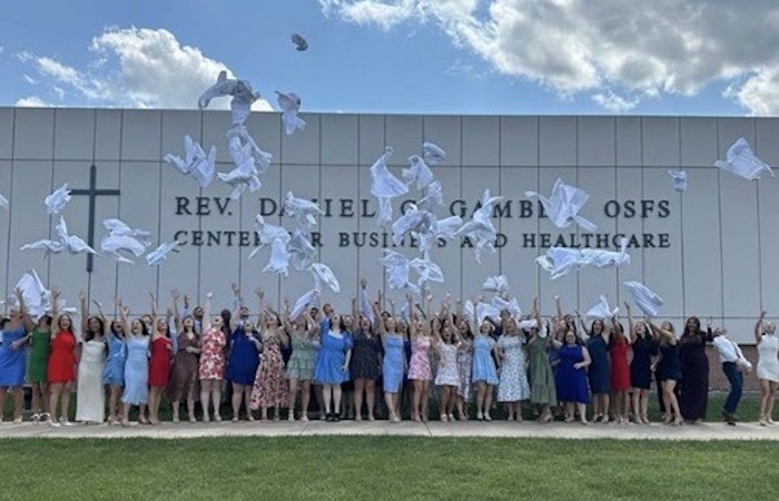 Graduating PA class throwing their white coats in the sky